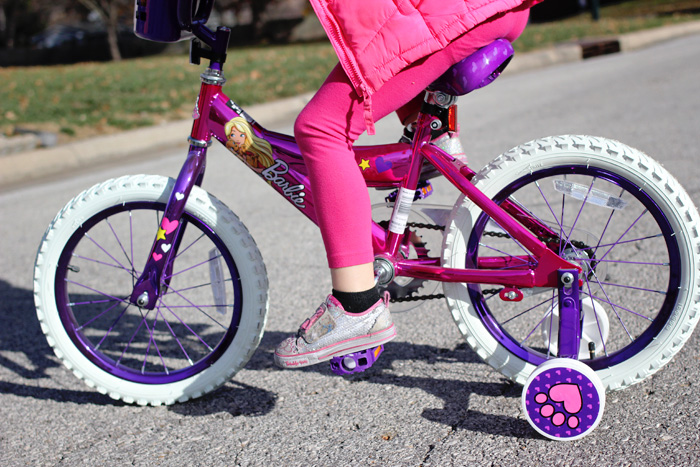 niña jugando en bicicleta de barbie
